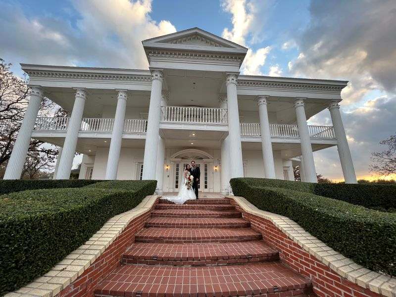 bride and groom outside white mansion