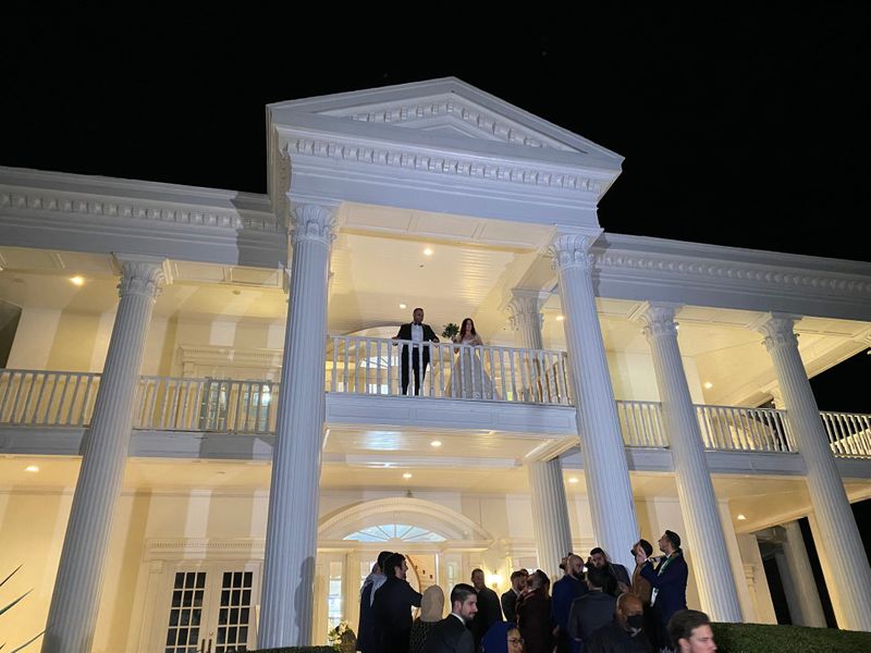 bride and groom on balcony of a white mansion