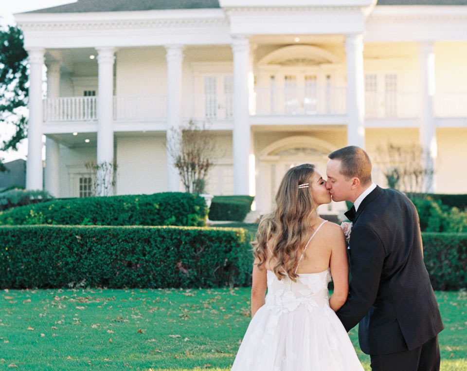 Couple kissing in front of Lone Star Mansion